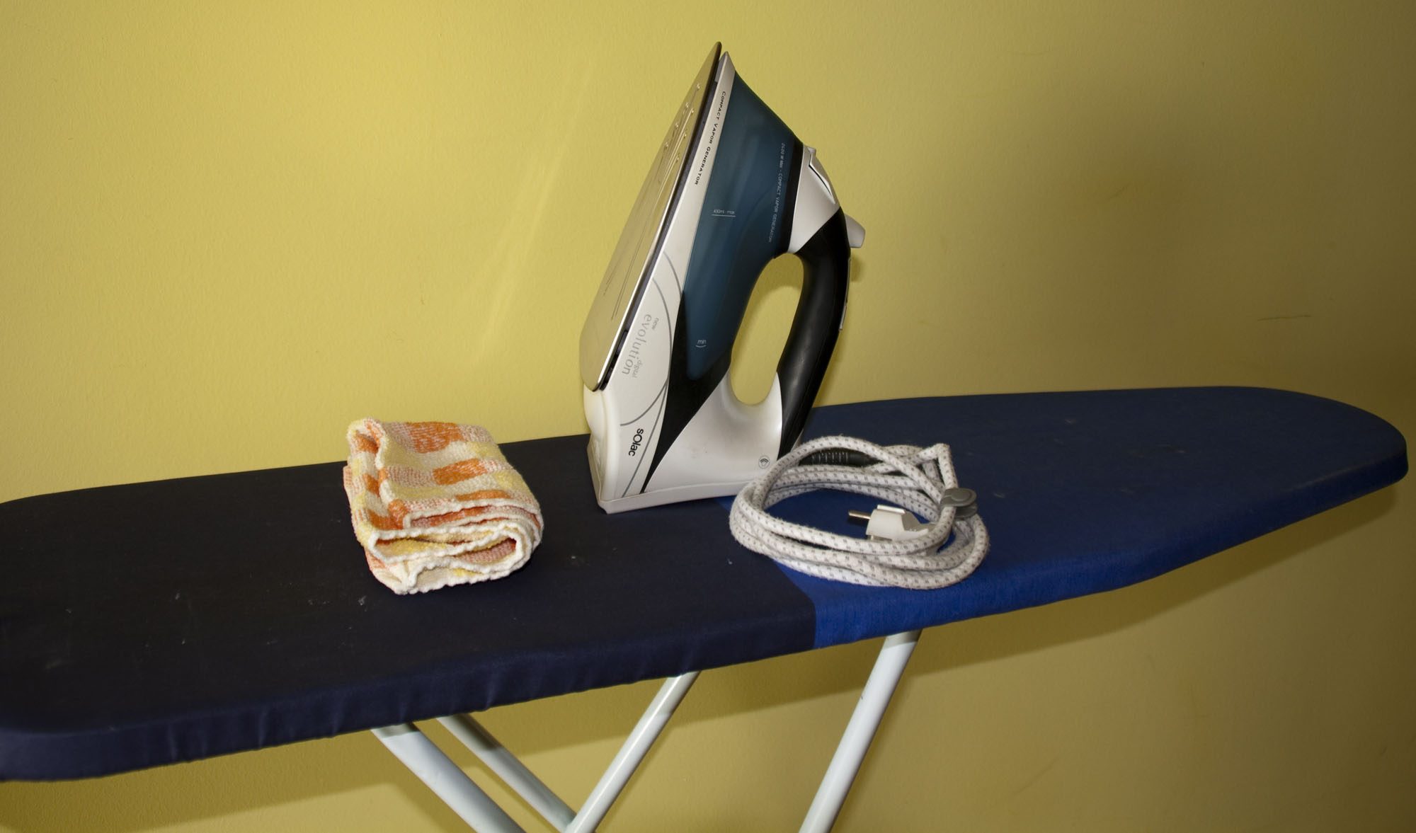 En la imagen: trapo de cocina, y plancha sobre una tabla de planchar.